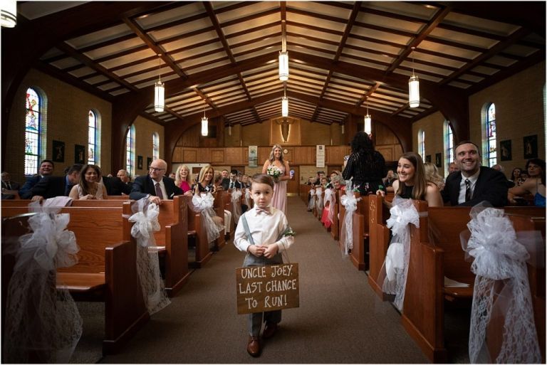 Ring Bearer walking down the aisle with adorable sign