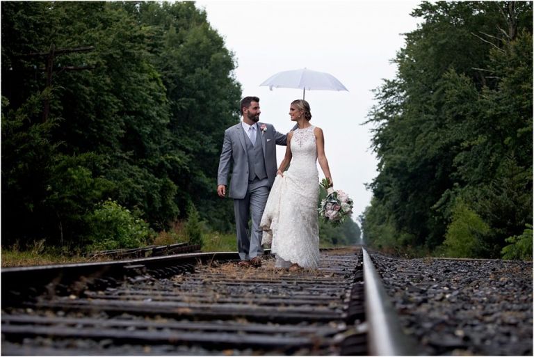 Groom walking with bride along train tracks at Everly at Railroad