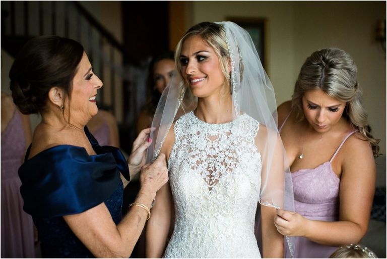 Maid of Honor and mother of bride putting brides veil on