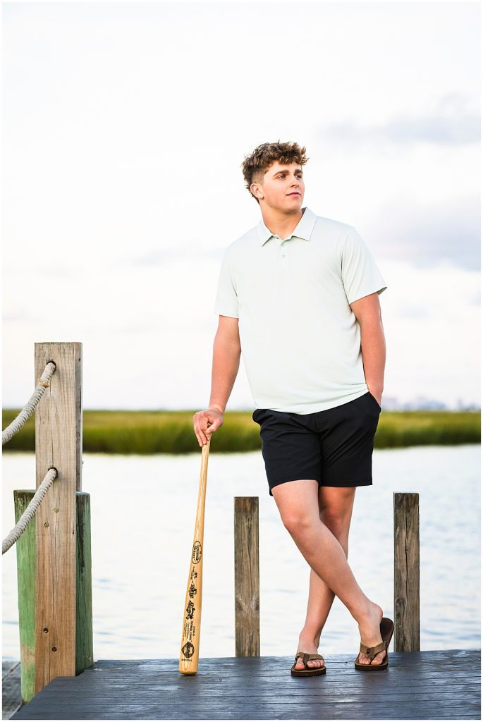 high school senior leaning against baseball bat with bay in the background