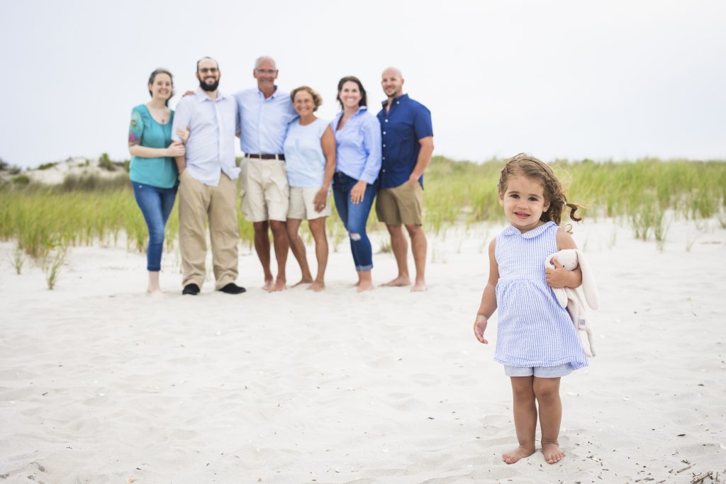 little girl standing in front of family during beach photo shoot