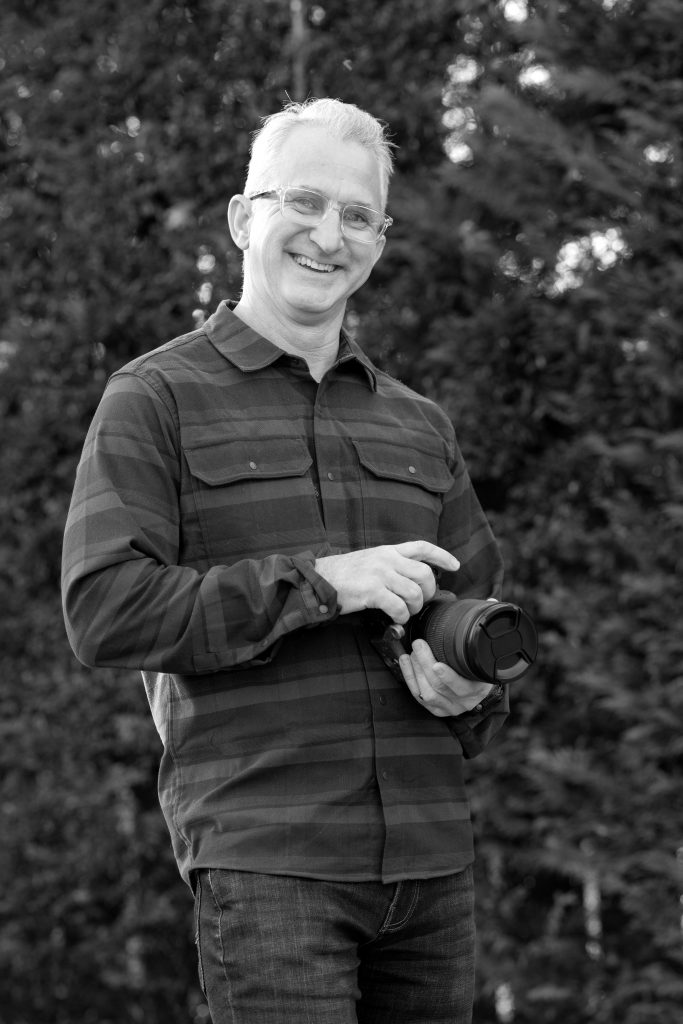 Dan Angelo holding camera in b&w