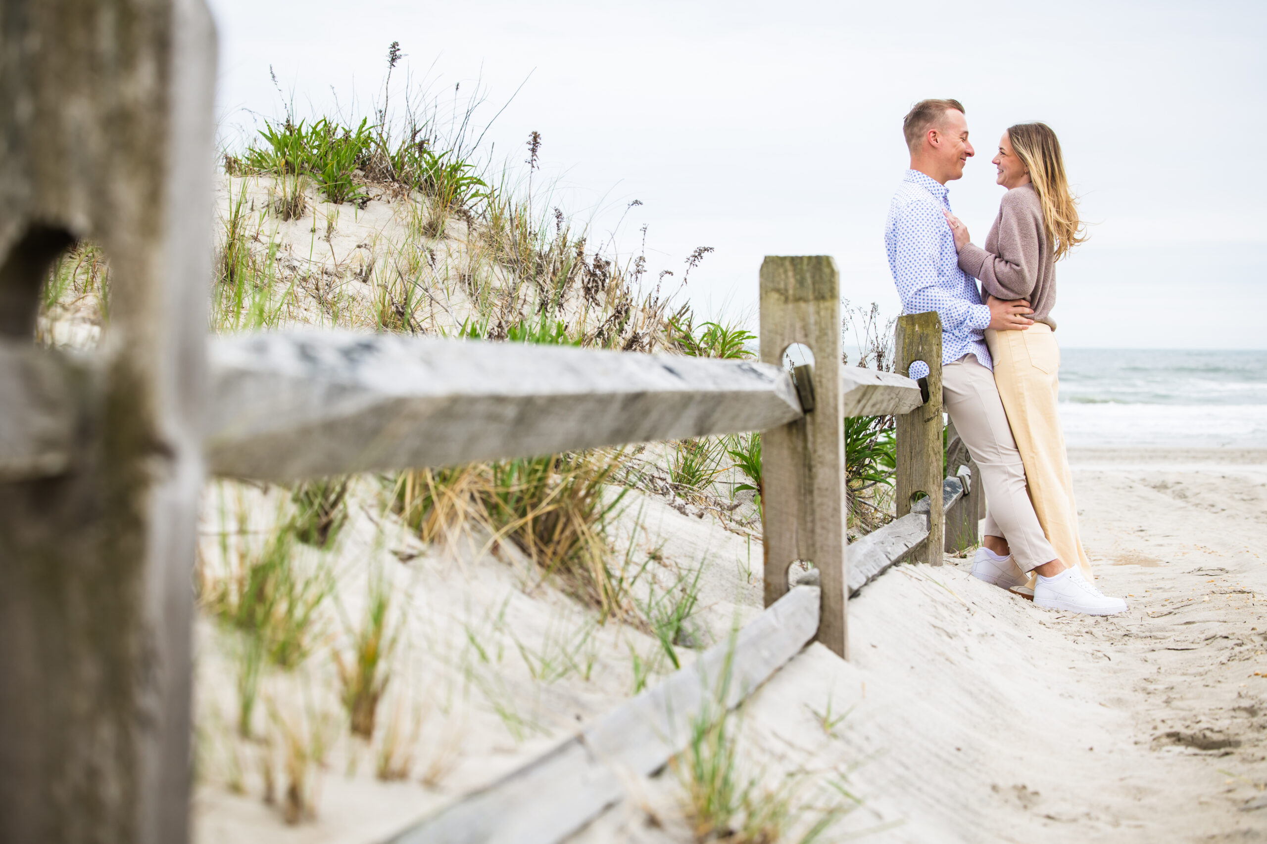 couple on beach along fence in stone harbor