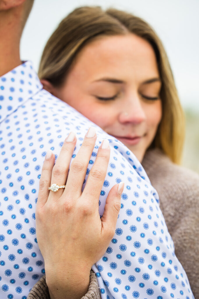 close up photo of engagement ring over man's shoulder